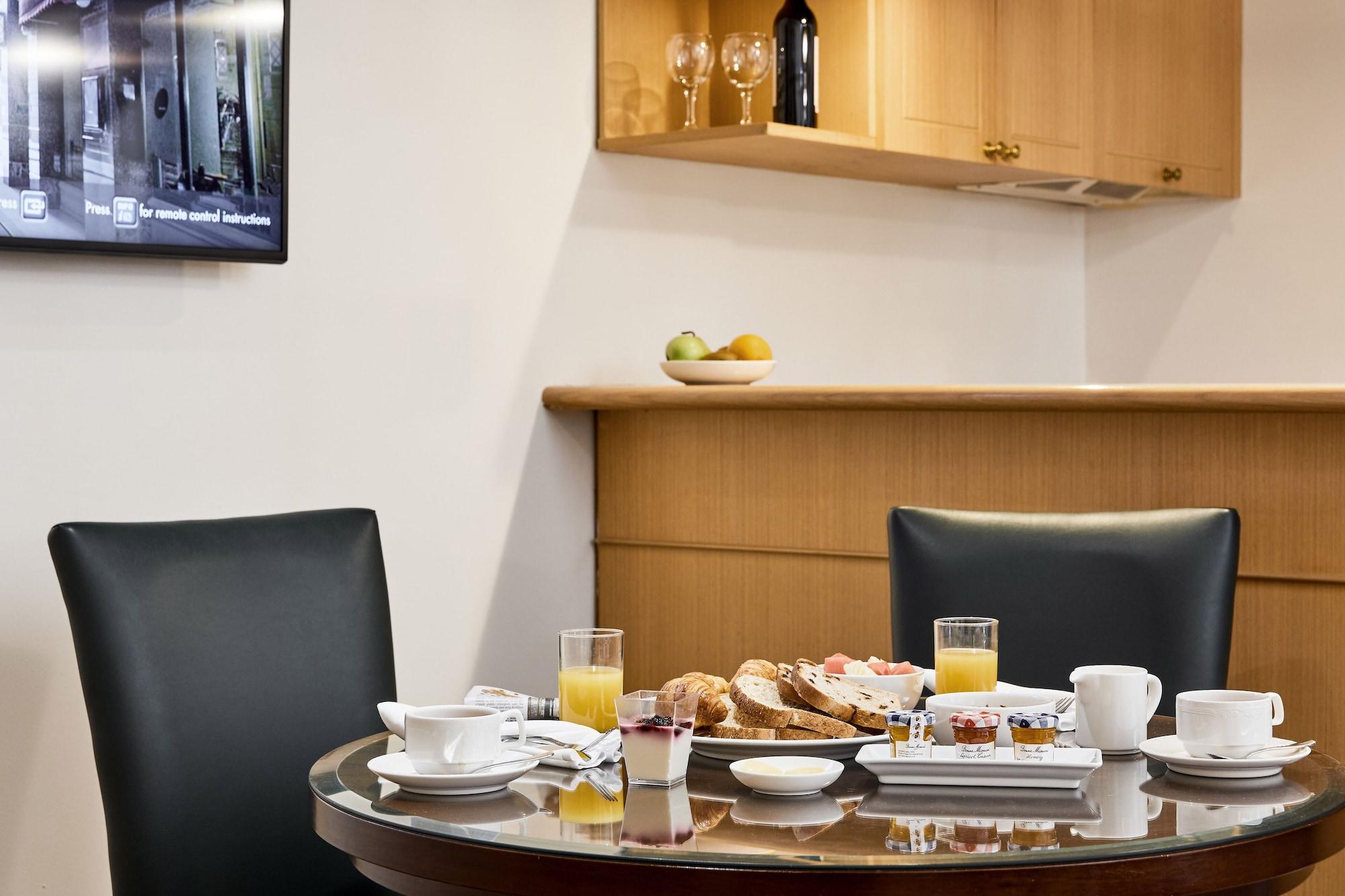 스탬포드 플라자 멜버른 호텔 멜번 외부 사진 The photo shows a dining table set for breakfast or brunch. There are several food items displayed, including pastries and bread. Additionally, there are drinks, such as orange juice, served in glasses, and coffee in white cups. The table is round an
