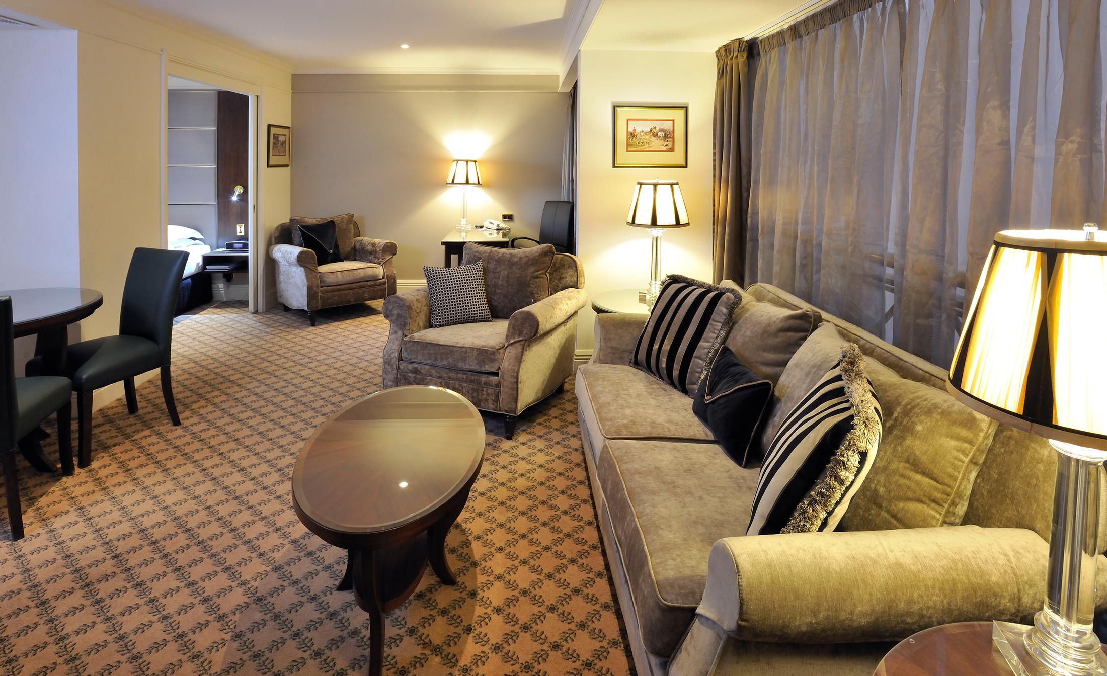 스탬포드 플라자 멜버른 호텔 멜번 외부 사진 The photo shows a stylish and comfortable living area. It features plush seating, including a sofa with decorative cushions and a couple of armchairs. There's a circular coffee table in the center of the seating arrangement. The room has soft lightin