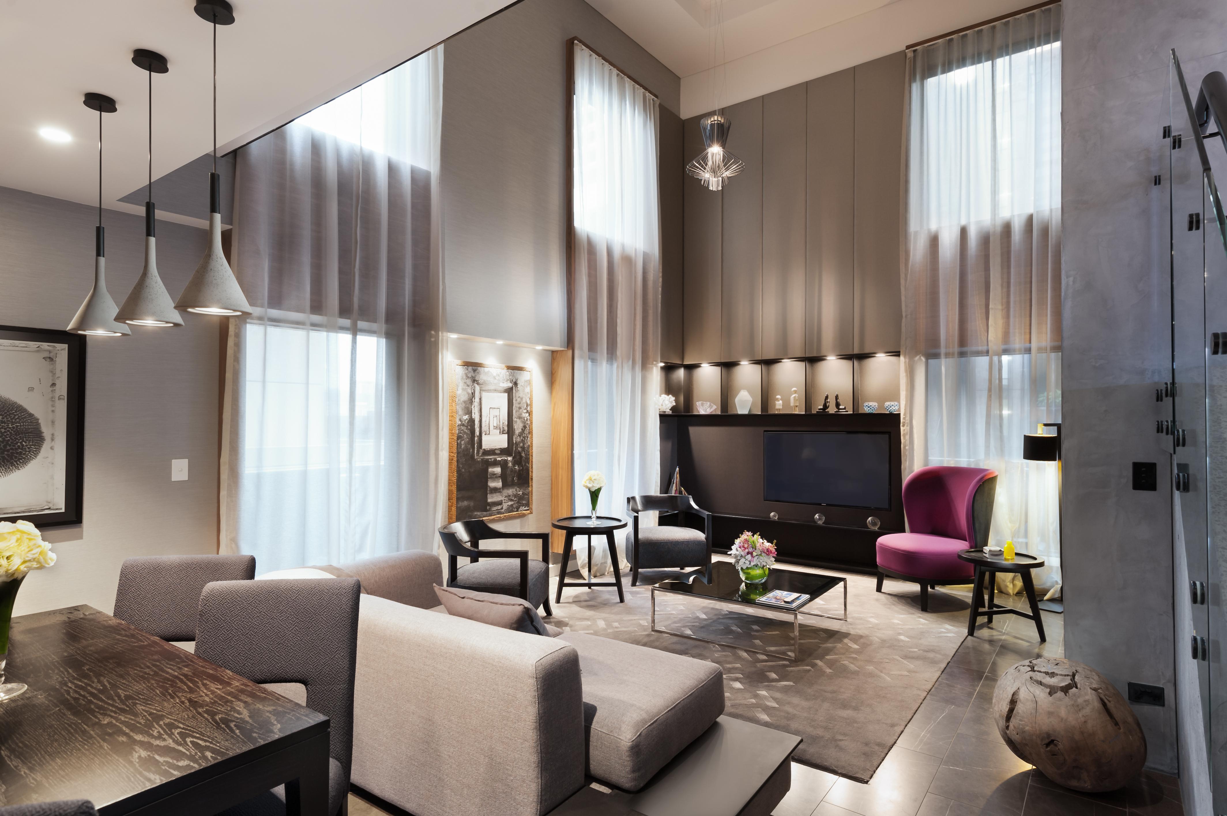 스탬포드 플라자 멜버른 호텔 멜번 외부 사진 The photo shows a stylish and modern living room with high ceilings and large windows that allow natural light to brighten the space. The room features a mix of contemporary furniture, including a light gray sofa and a sleek coffee table in the cente