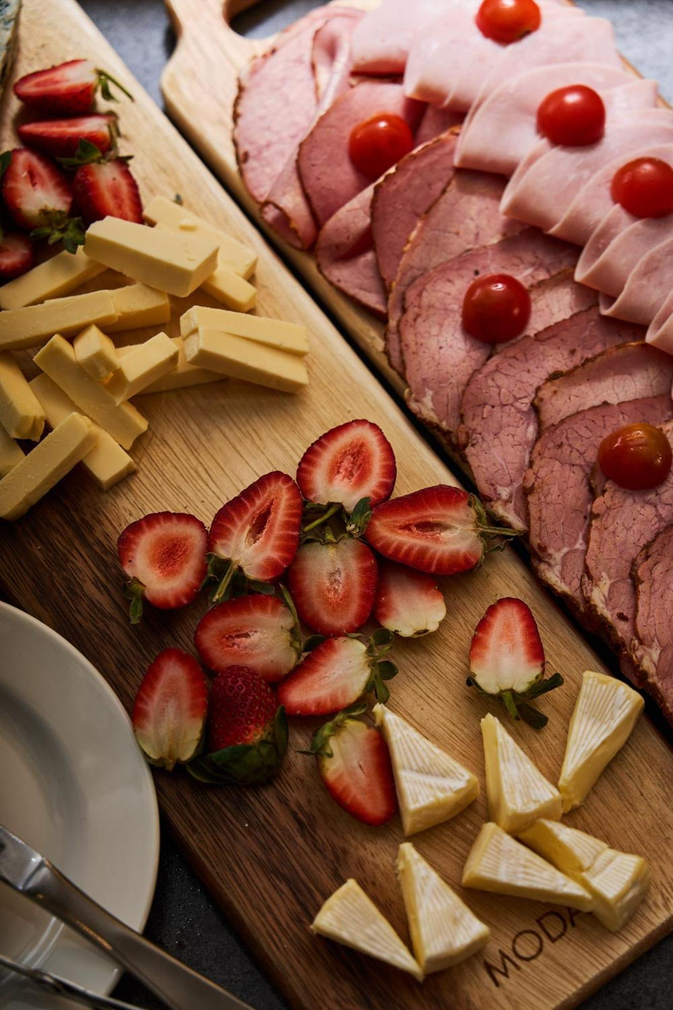스탬포드 플라자 멜버른 호텔 멜번 외부 사진 The photo displays an assortment of food items arranged on a wooden surface. There are slices of various meats, including ham, alongside round cherry tomatoes. Next to the meat, there are several pieces of yellow cheese cut into sticks. Additionally,