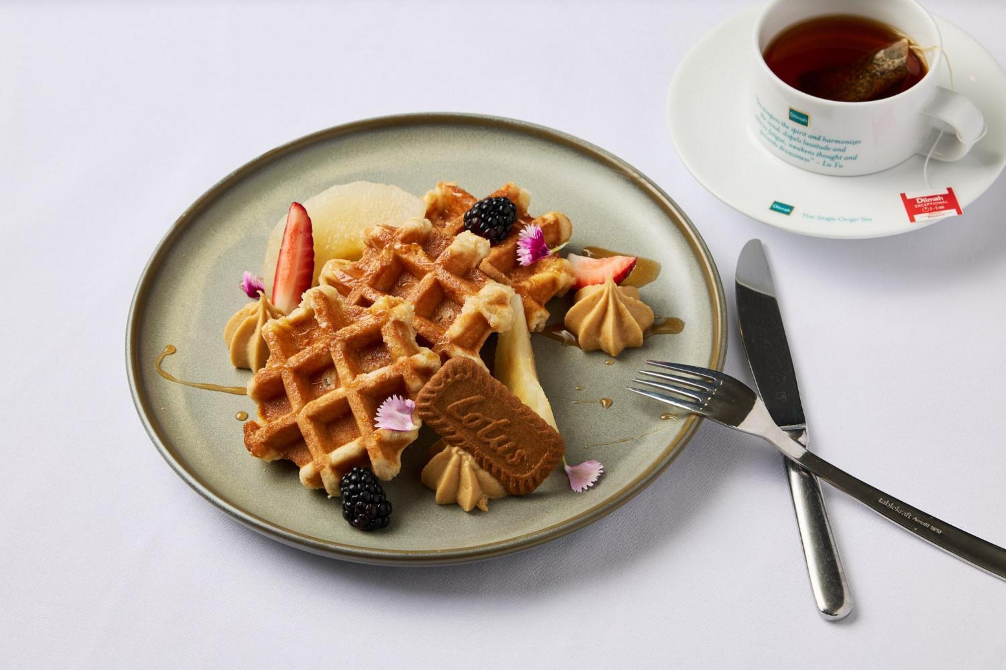 스탬포드 플라자 멜버른 호텔 멜번 외부 사진 The photo depicts a beautifully arranged plate of waffles. The waffles are topped with a variety of accompaniments including slices of fresh fruit, blackberries, and small dollops of cream or mousse. A decorative cookie is placed on the waffles, addi