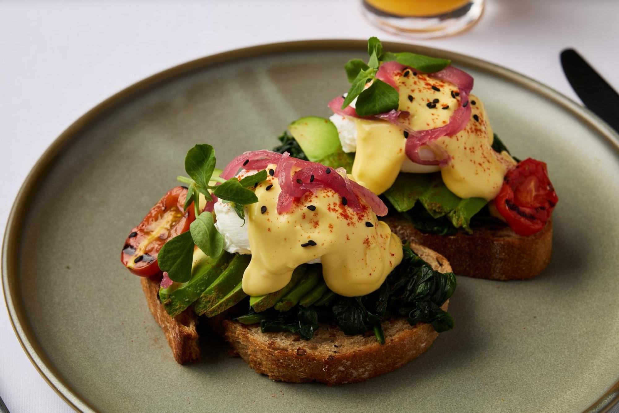스탬포드 플라자 멜버른 호텔 멜번 외부 사진 The photo shows a plate featuring two pieces of toasted bread topped with a variety of ingredients. Each slice is layered with sautéed spinach and other greens, along with slices of cucumber and cherry tomatoes. The dish is finished with poached eggs