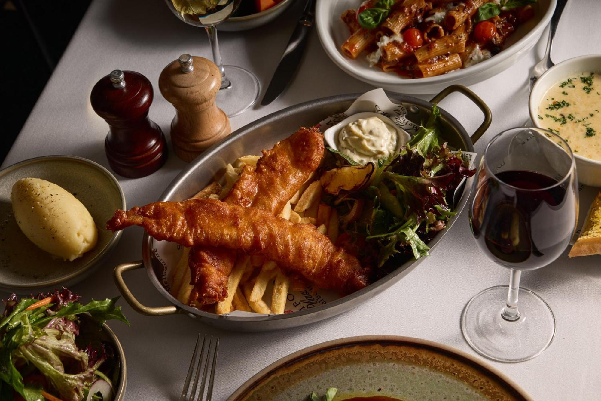 스탬포드 플라자 멜버른 호텔 멜번 외부 사진 The photo showcases a beautifully arranged meal. In the foreground, there are two pieces of golden-battered fish served with crispy fries. Accompanying the fish is a small dollop of creamy sauce and a side salad, which has a mix of greens. Surroundin