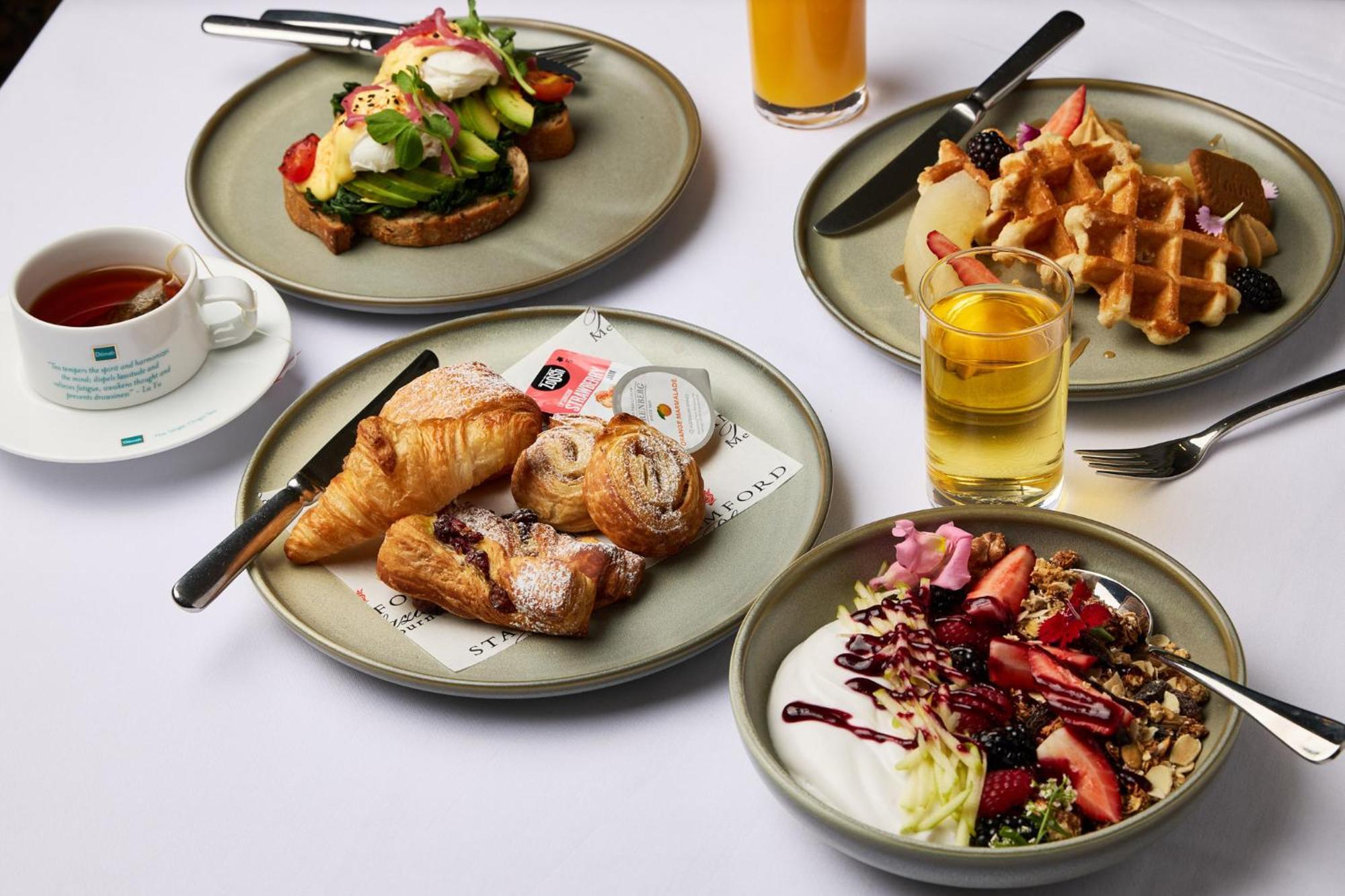스탬포드 플라자 멜버른 호텔 멜번 외부 사진 The photo displays a variety of breakfast items arranged on several plates. 

1. **Top-left Plate**: Features an open-faced sandwich with avocado, topped with poached eggs and garnished with vegetables.
2. **Top-right Plate**: Contains freshly made w